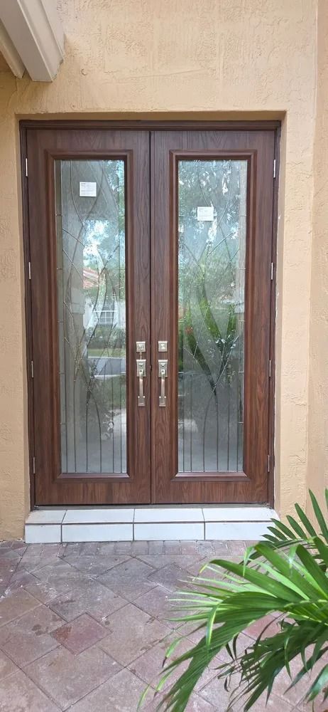 Brown double front doors with glass panes and a tiled doorstep