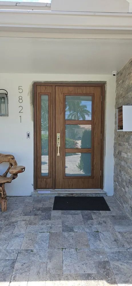 Wood-framed glass front door with stone entryway and black doormat at house 5821