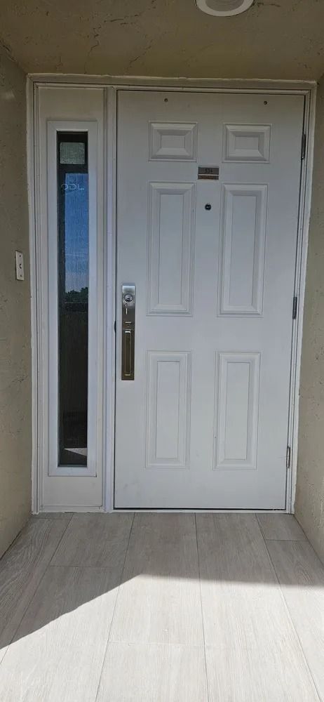White front door with a narrow glass side panel and concrete porch steps in front