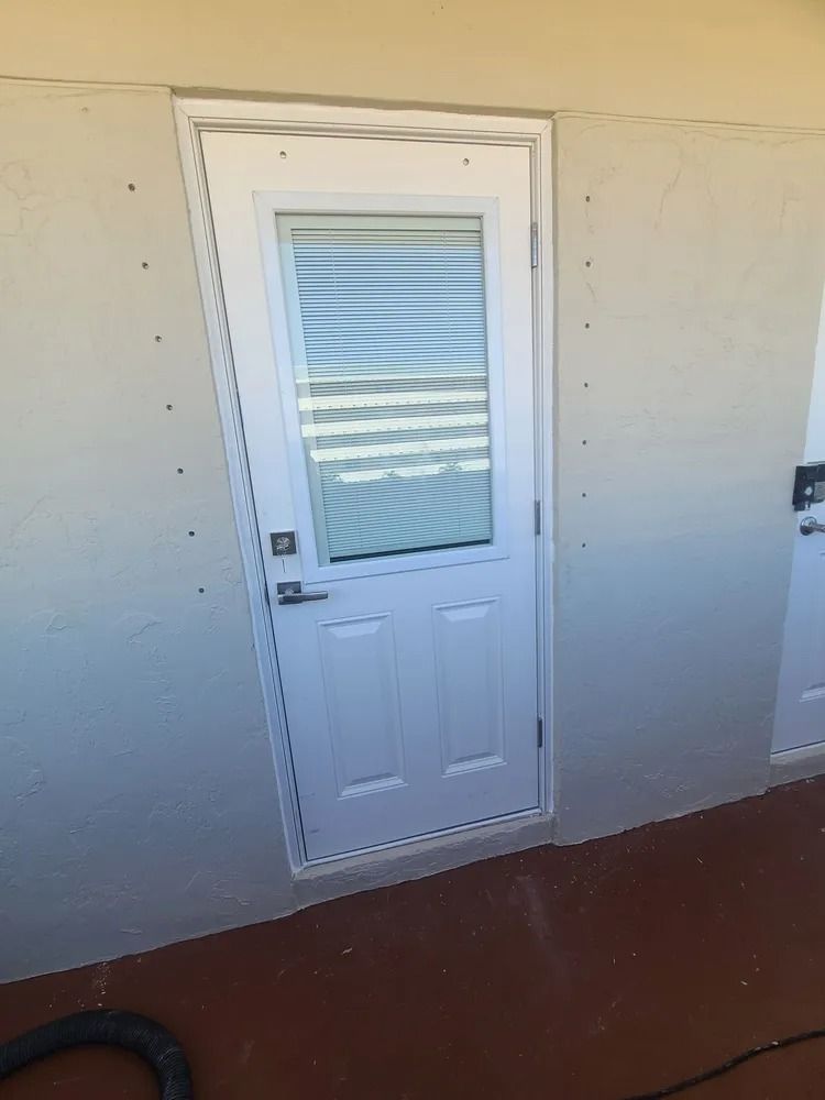 White exterior door with a frosted glass panel on a beige wall, with red flooring below.