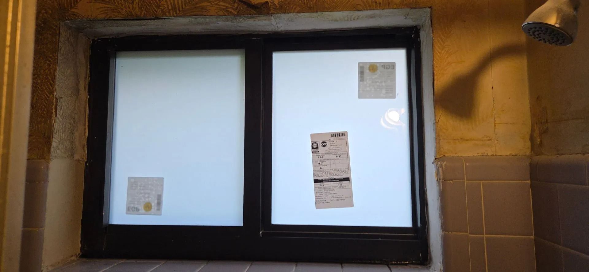 Stone-framed window with frosted panes and posted notices on a tiled wall