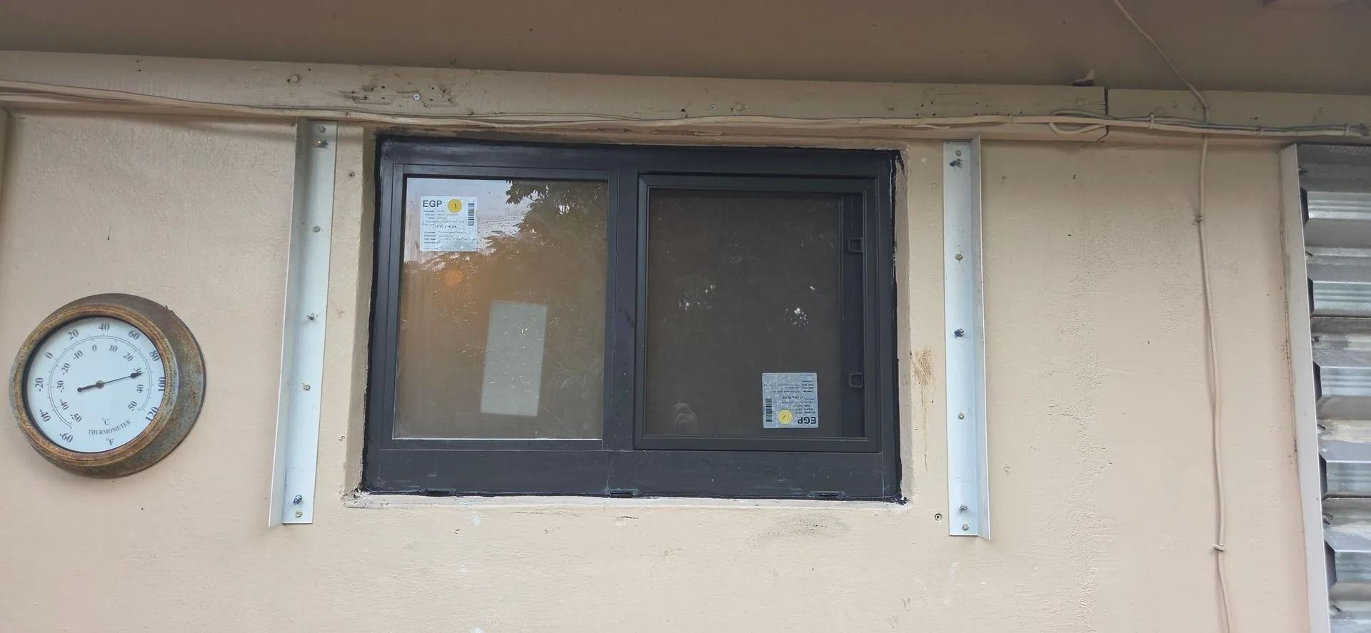 Wall with a small dark window, mounted sign brackets, and a round clock on the left.