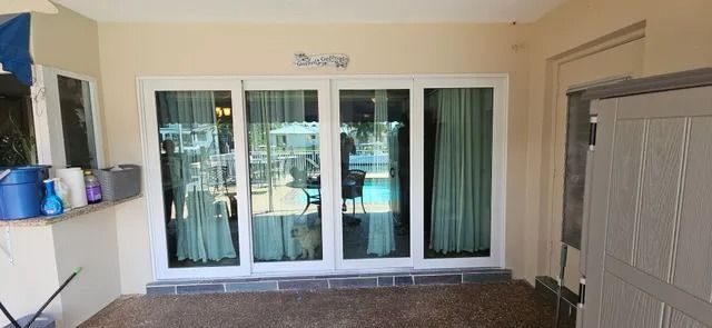 Patio with white sliding glass doors, beige walls, and a gray garage door on the right.