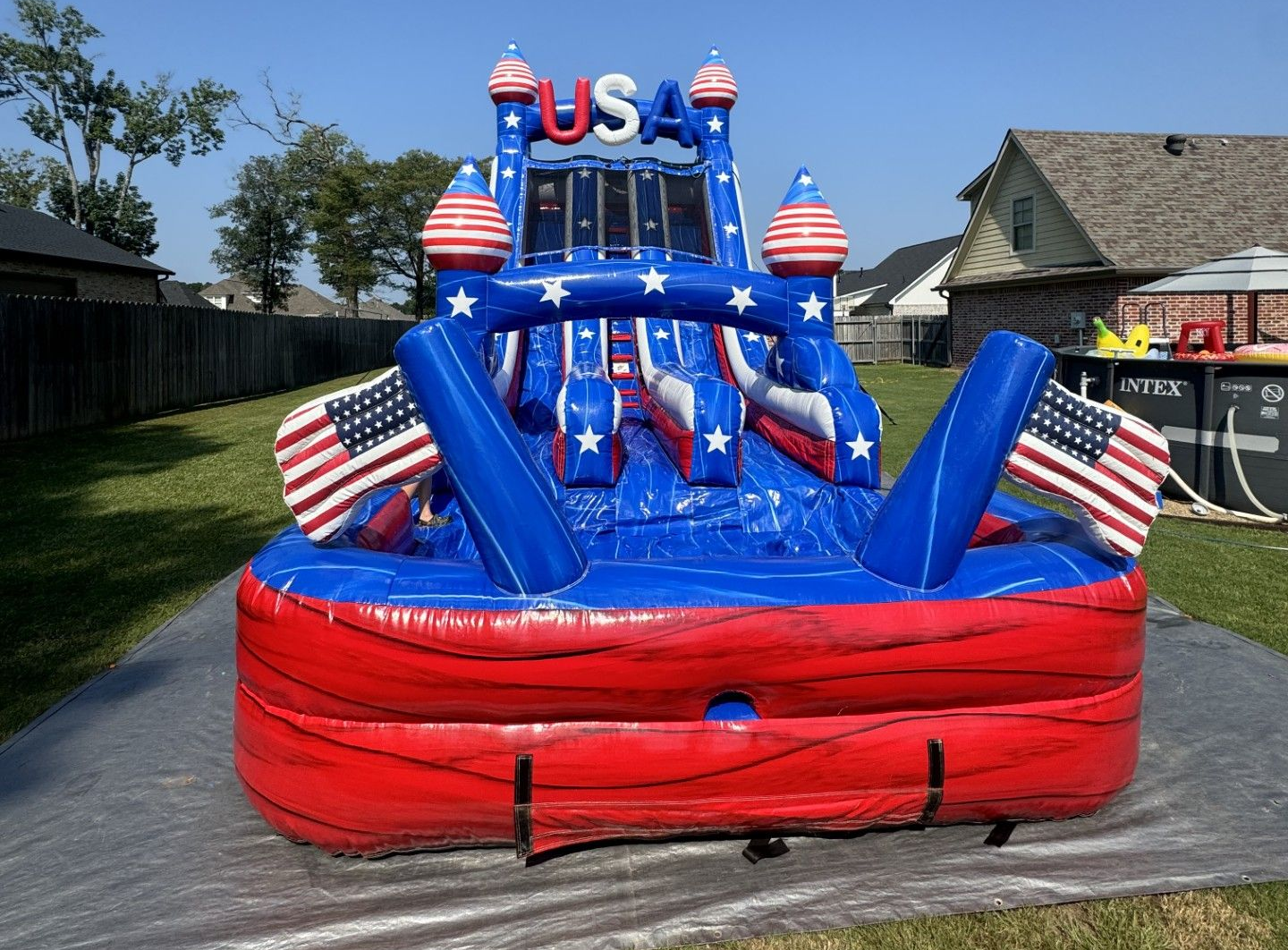 Red, white, and blue USA-themed inflatable bounce house in a backyard