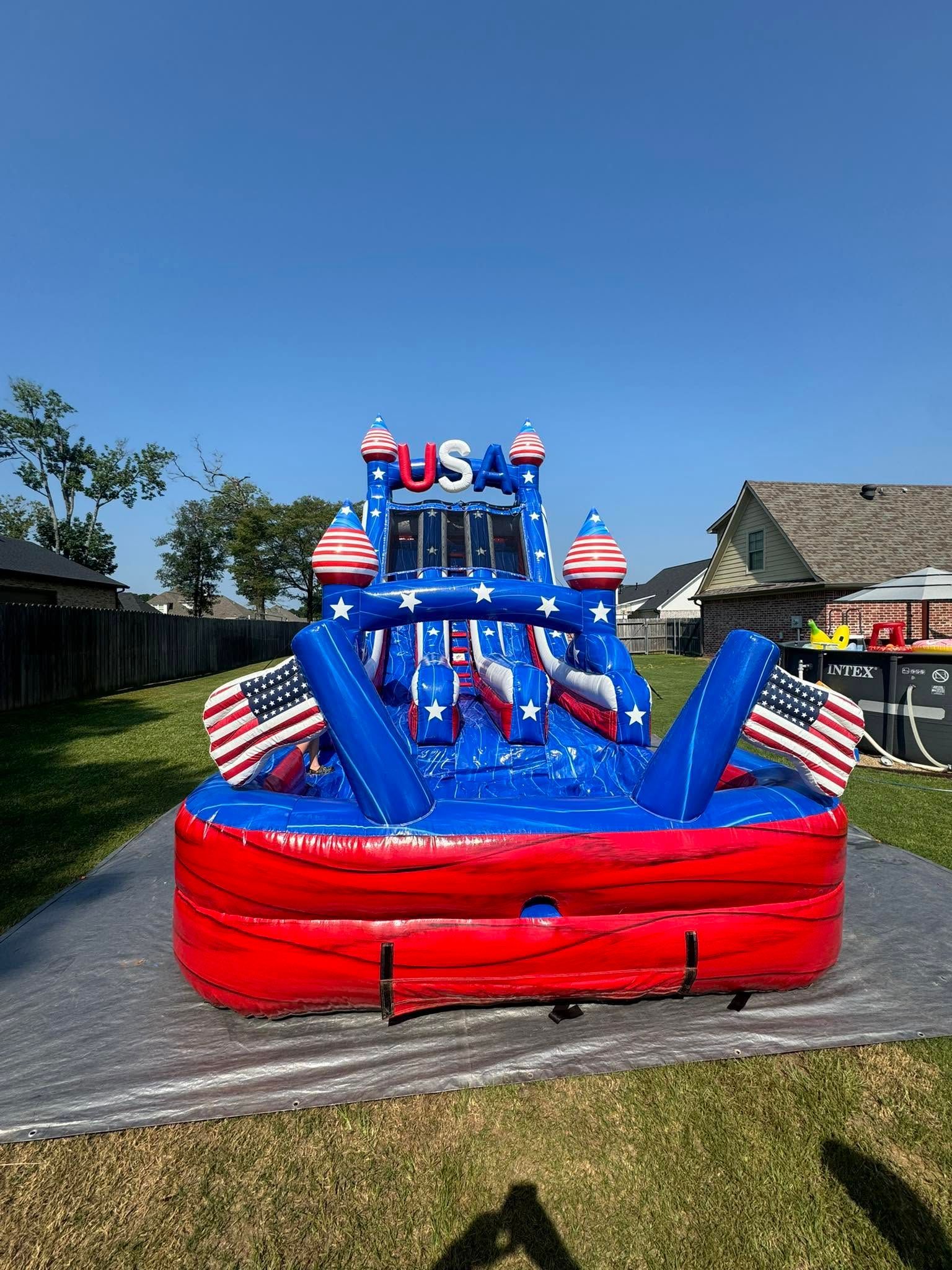 Red, white, and blue inflatable obstacle course with stars and stripes on a sunny lawn.