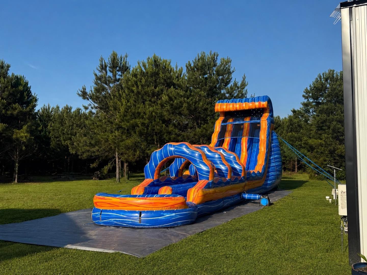 Blue and orange inflatable obstacle course on grass under a clear sky
