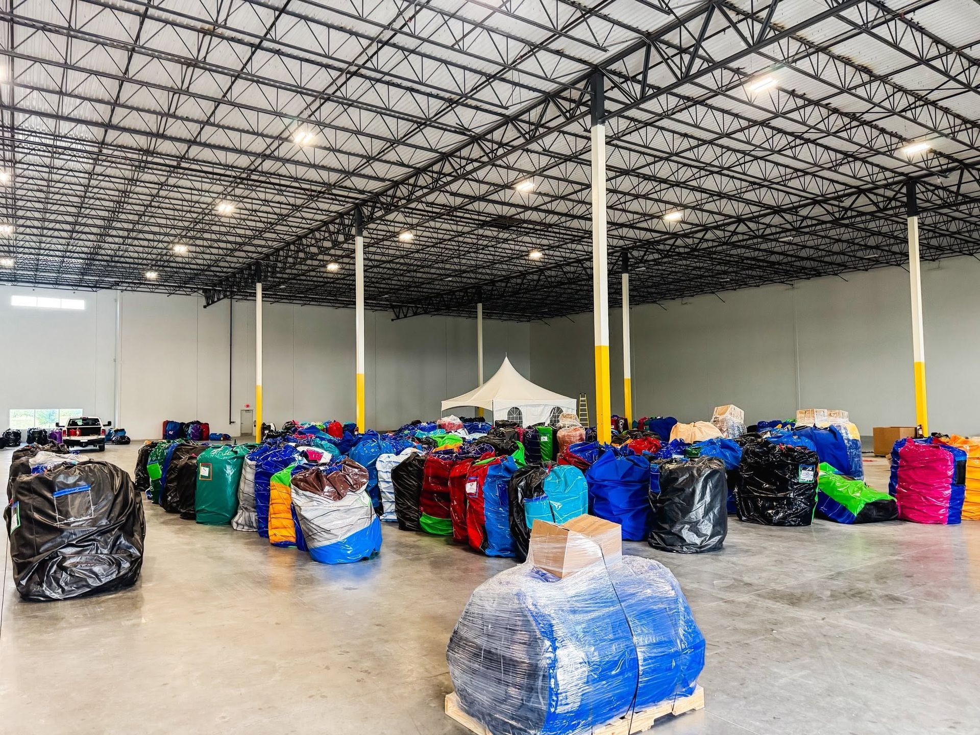 Large warehouse with rows of colorful wrapped bales on the floor under a high metal ceiling