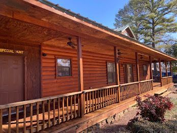 A log cabin with a large porch and a ceiling fan.