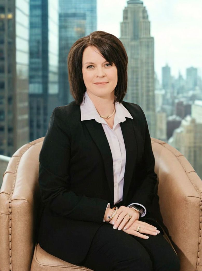 A woman in a black suit and white shirt with her arms crossed