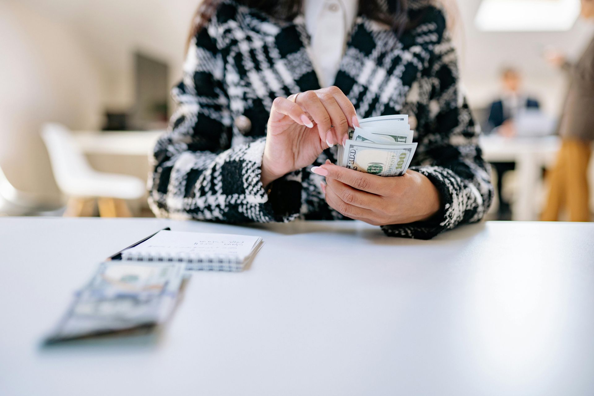 A woman is sitting at a table counting money.