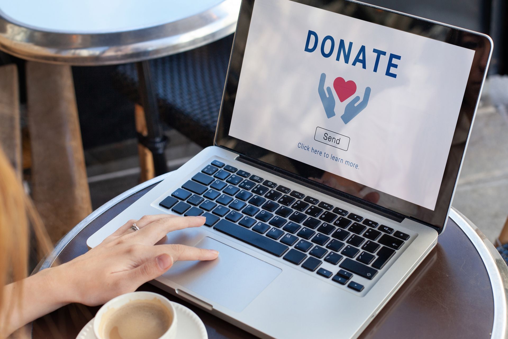 A person is sitting at a table with a laptop and a cup of coffee.