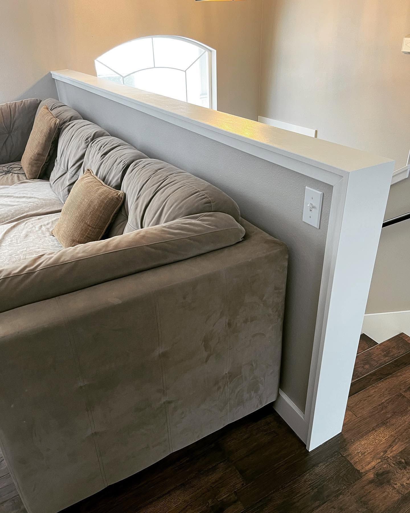 Living room with a gray sectional sofa beside a white half wall and a window seat niche