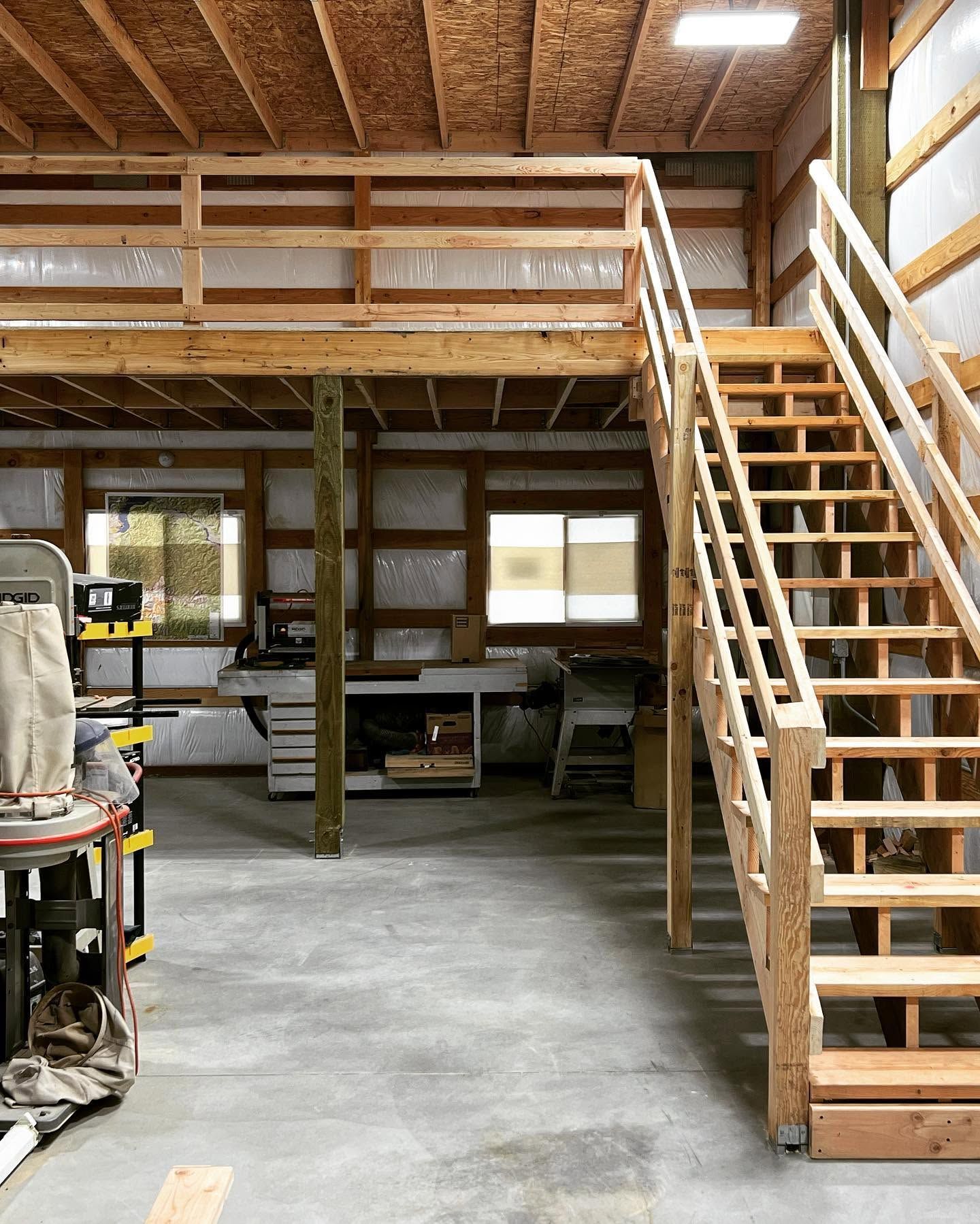 Warehouse interior with a wooden mezzanine and staircase above a concrete floor