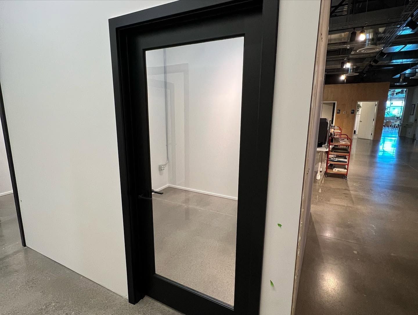 Black-framed full-length mirror leaning against a white wall in an industrial-style room
