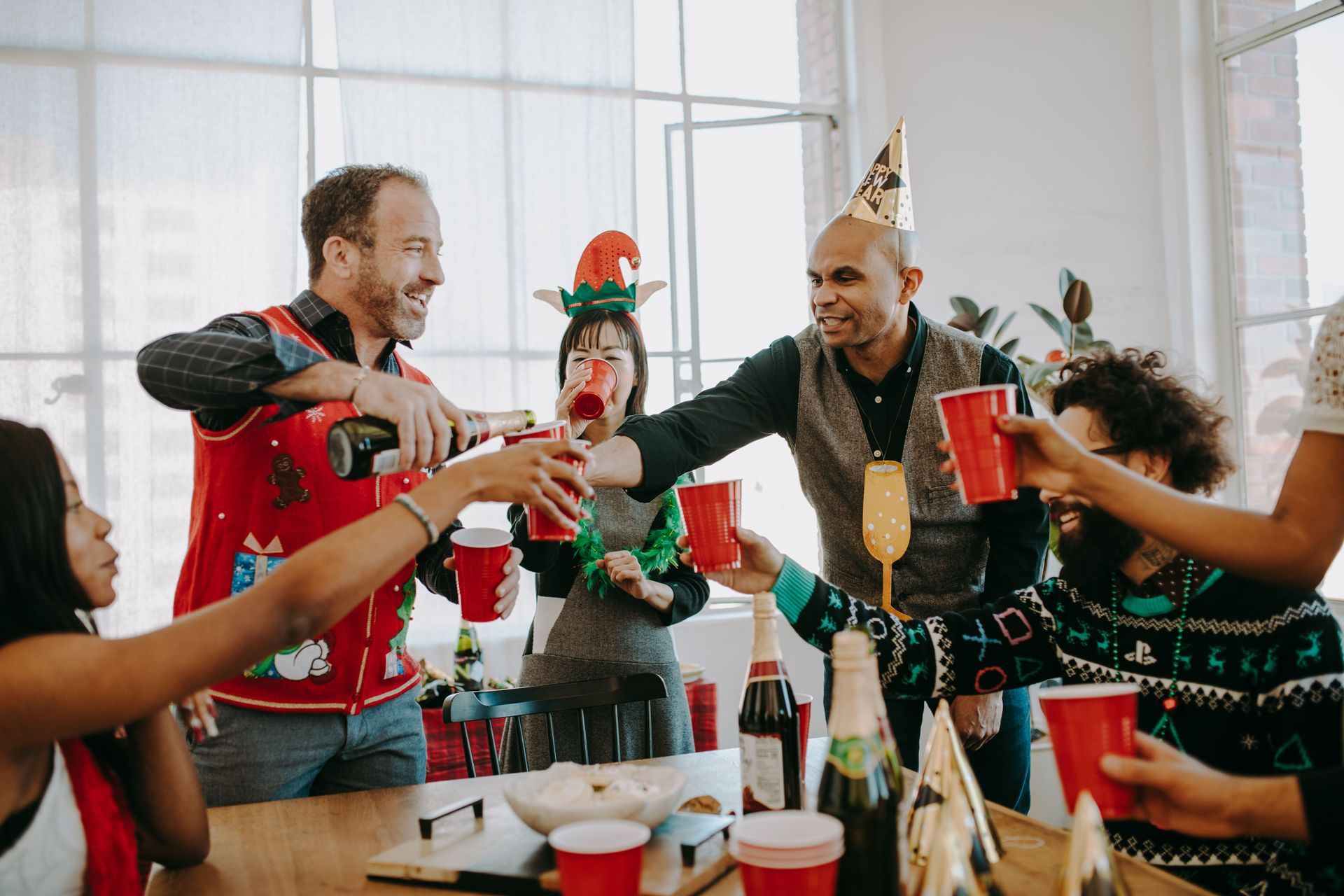 Friends raising drinks at a festive table with holiday decorations and smiling faces