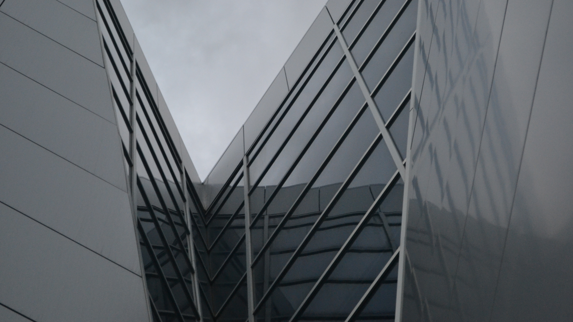 Modern glass building courtyard with triangular facades and reflective gray walls