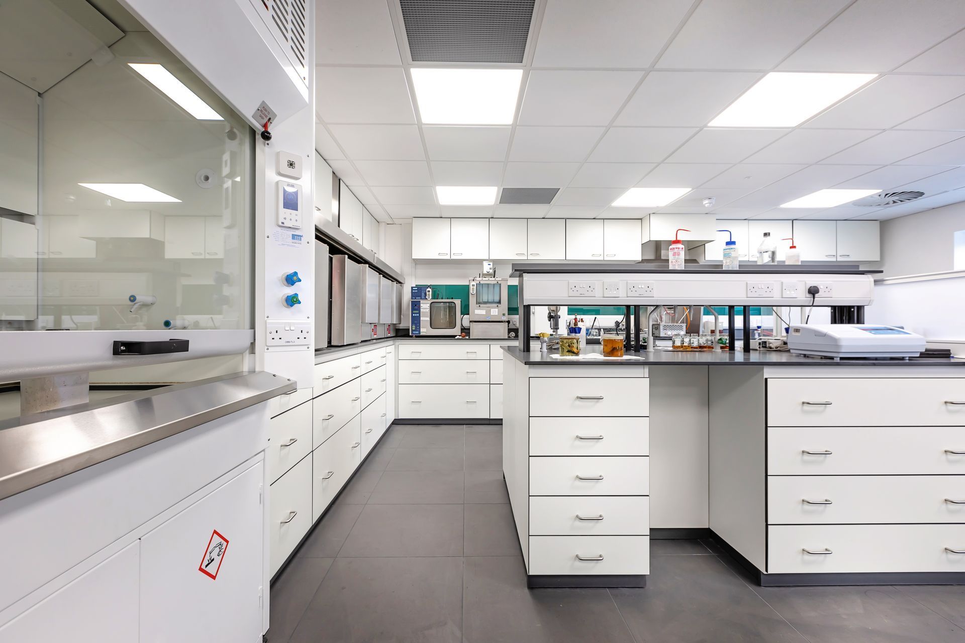 Bright laboratory with white cabinets, dark floor, and lab benches under fluorescent lights.