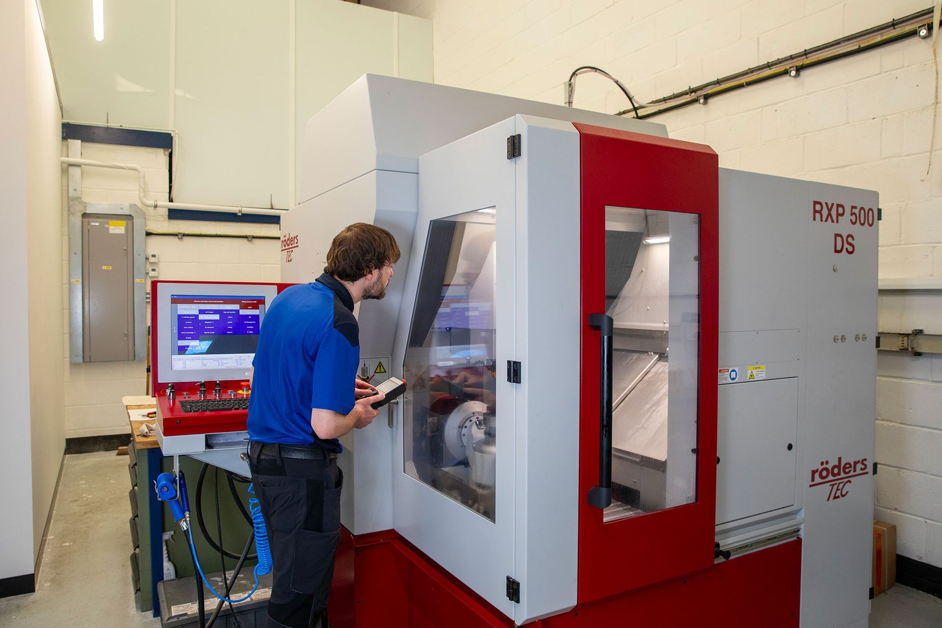 Person operating a red and white industrial machine in a lab or workshop
