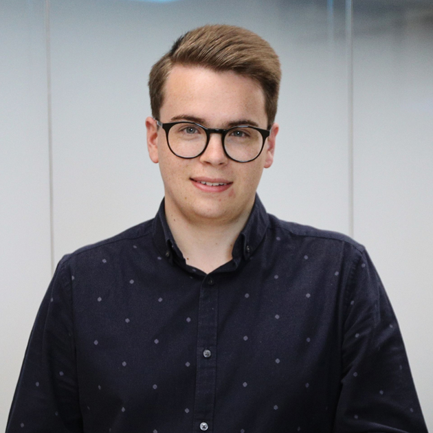 Portrait of a man with glasses in a dark button-up shirt against a light gray background