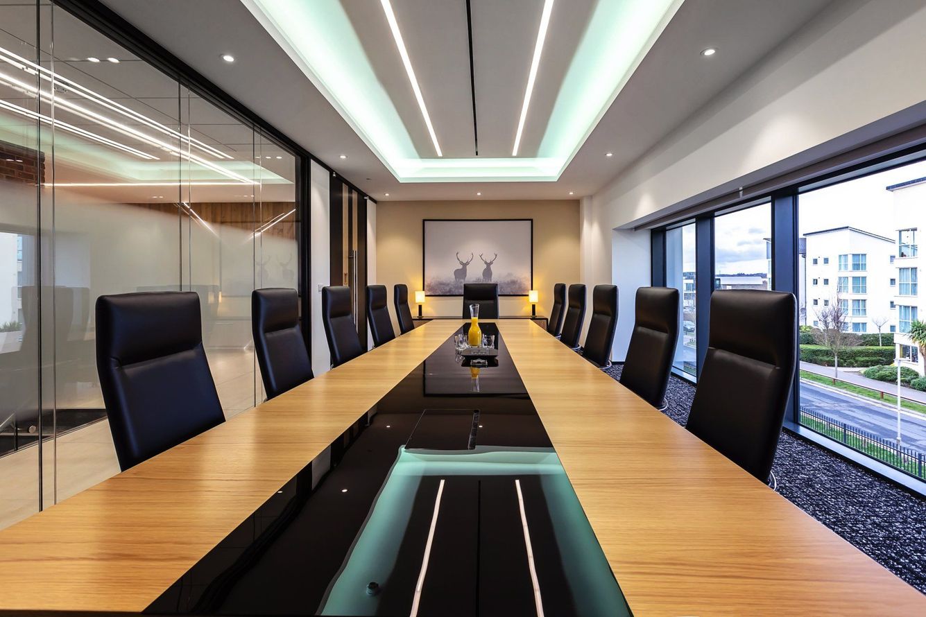 Modern conference room with a long wooden table, black chairs, and large windows