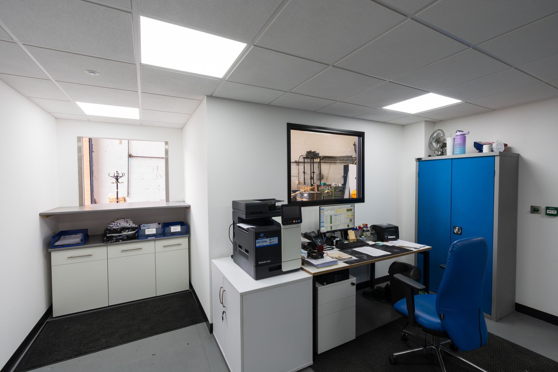 Person working at a desk with dual monitors in a bright office, viewing technical software on screen