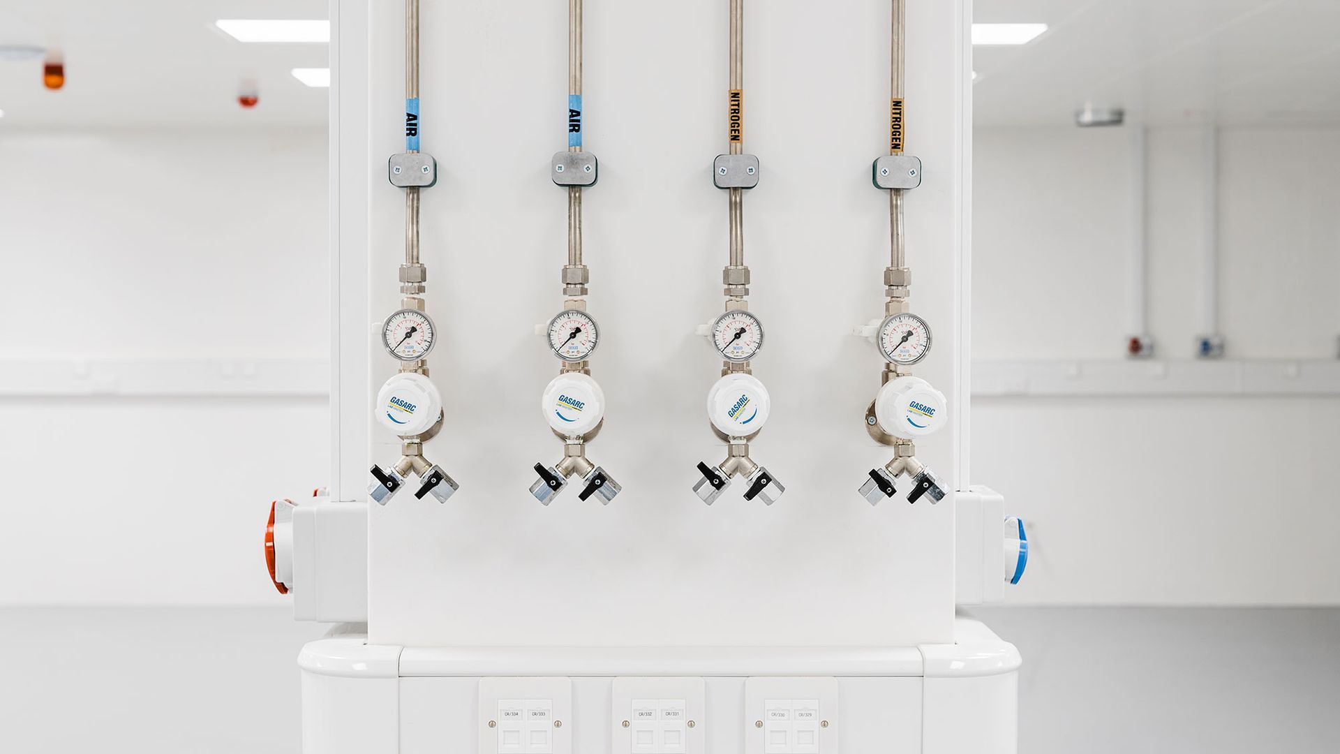 White interior with four hanging medical gas outlets and wall-mounted equipment panels