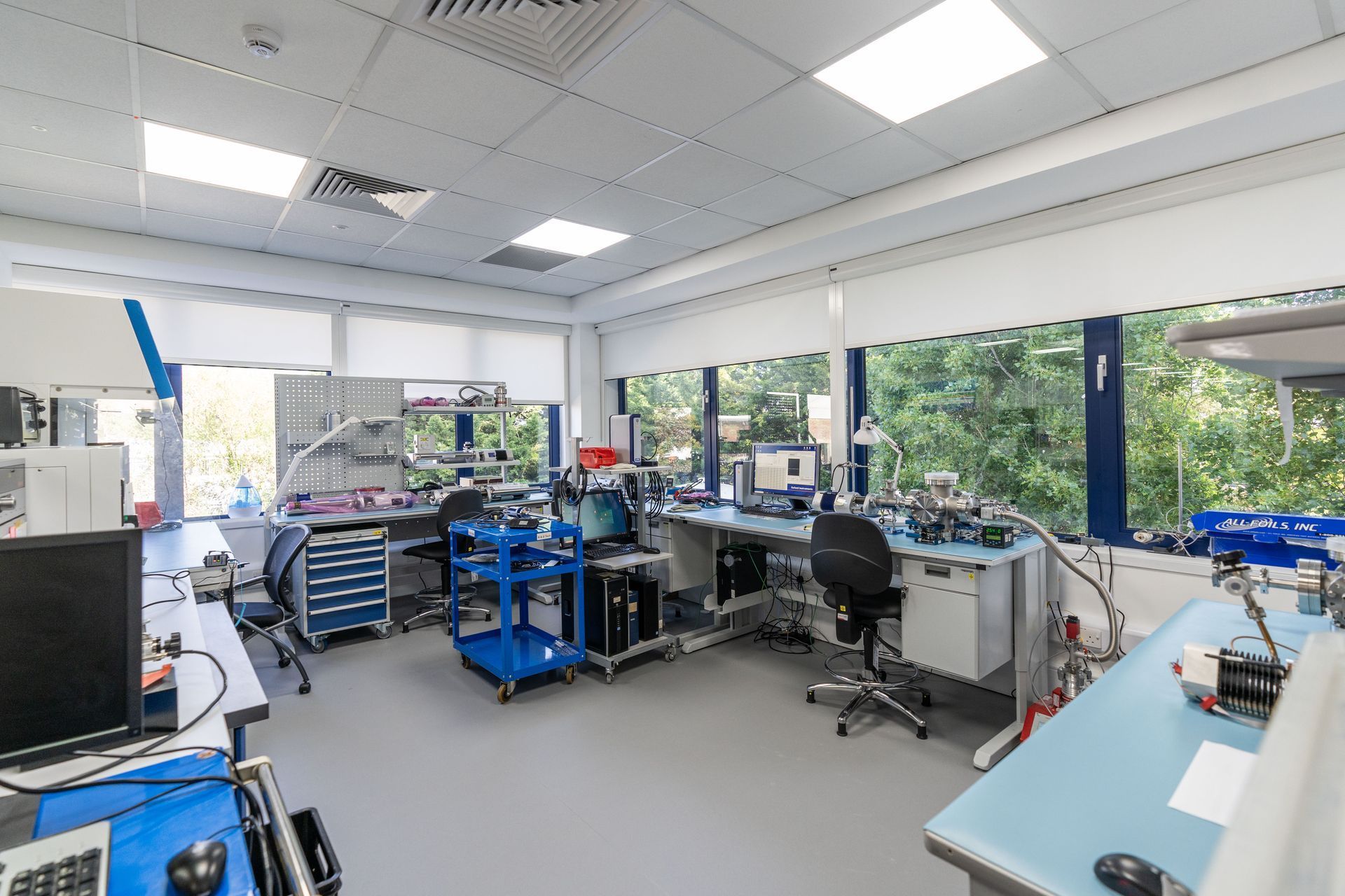 Bright laboratory workspace with workbenches, equipment, and large windows overlooking trees