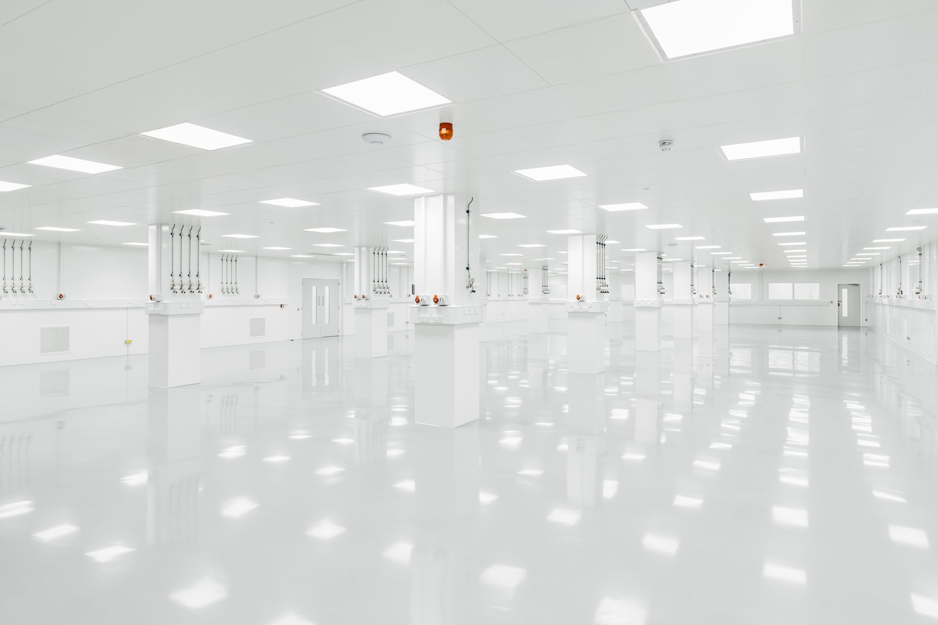 Bright, empty white industrial room with glossy floors and overhead lights