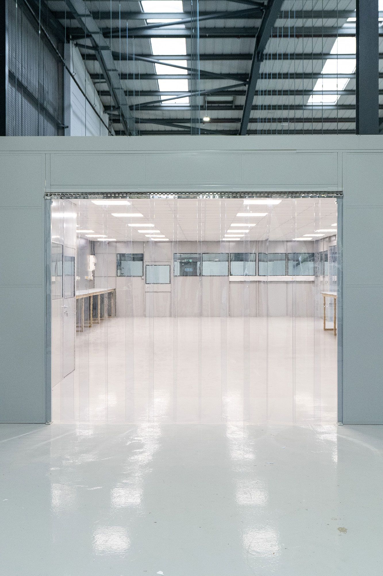 Empty modern warehouse interior with a large open doorway and glossy white floor