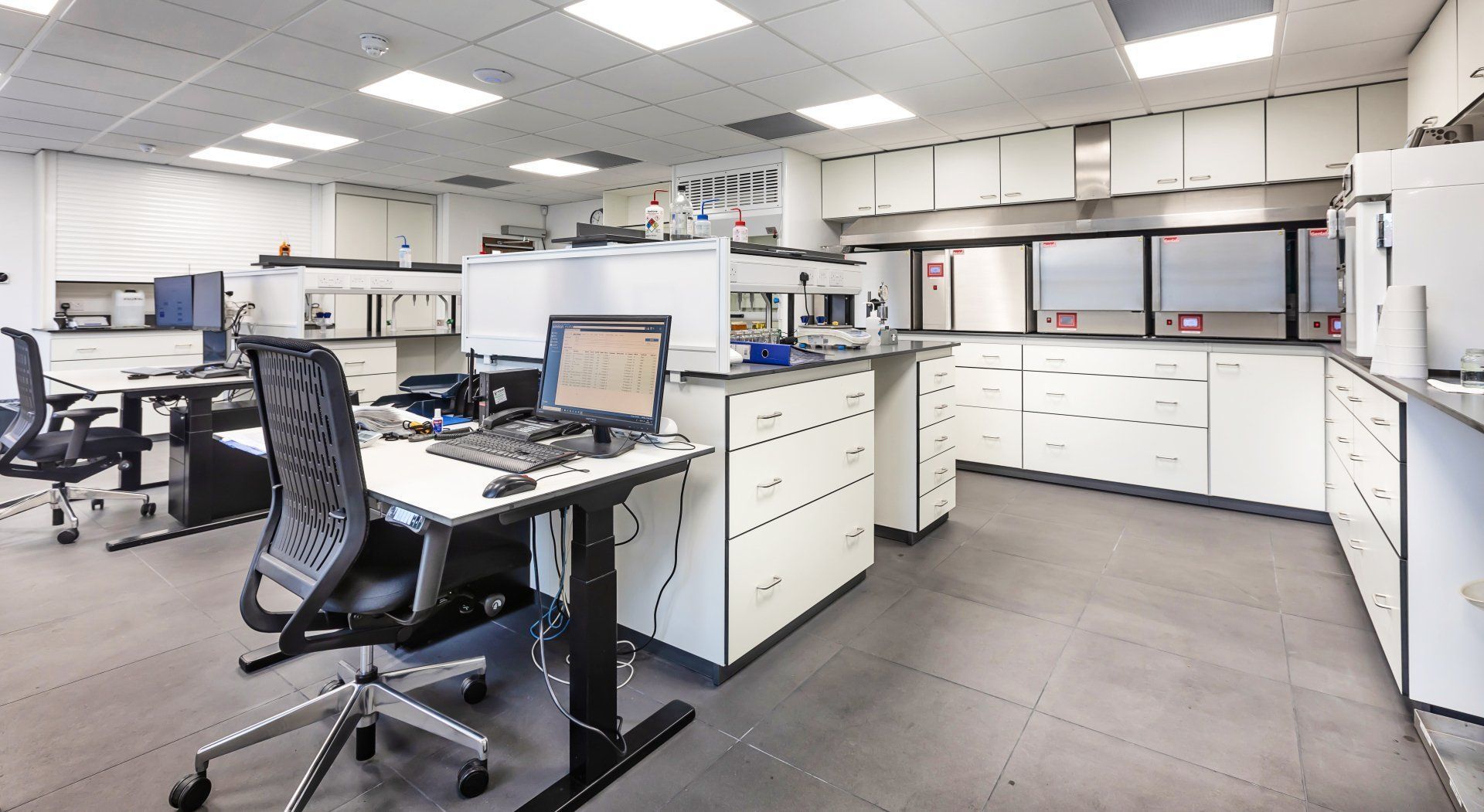 Bright laboratory workspace with workbenches, equipment, and large windows overlooking trees