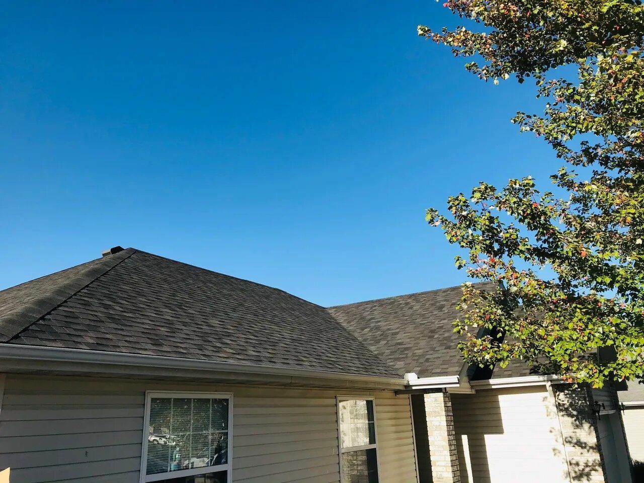 A house with a roof and a tree in front of it.
