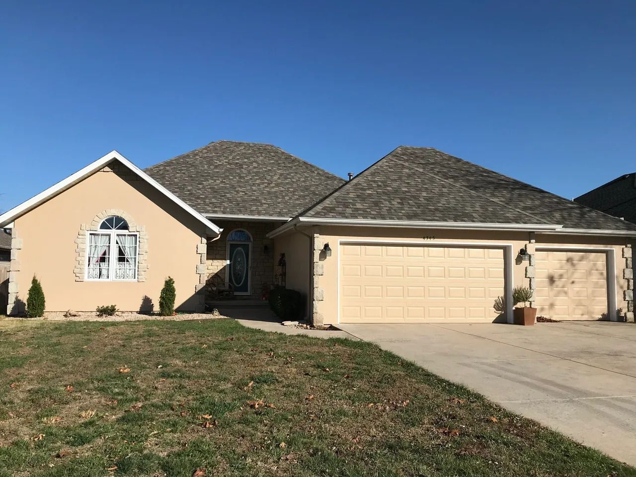 A house with two garage doors and a blue sky in the background.