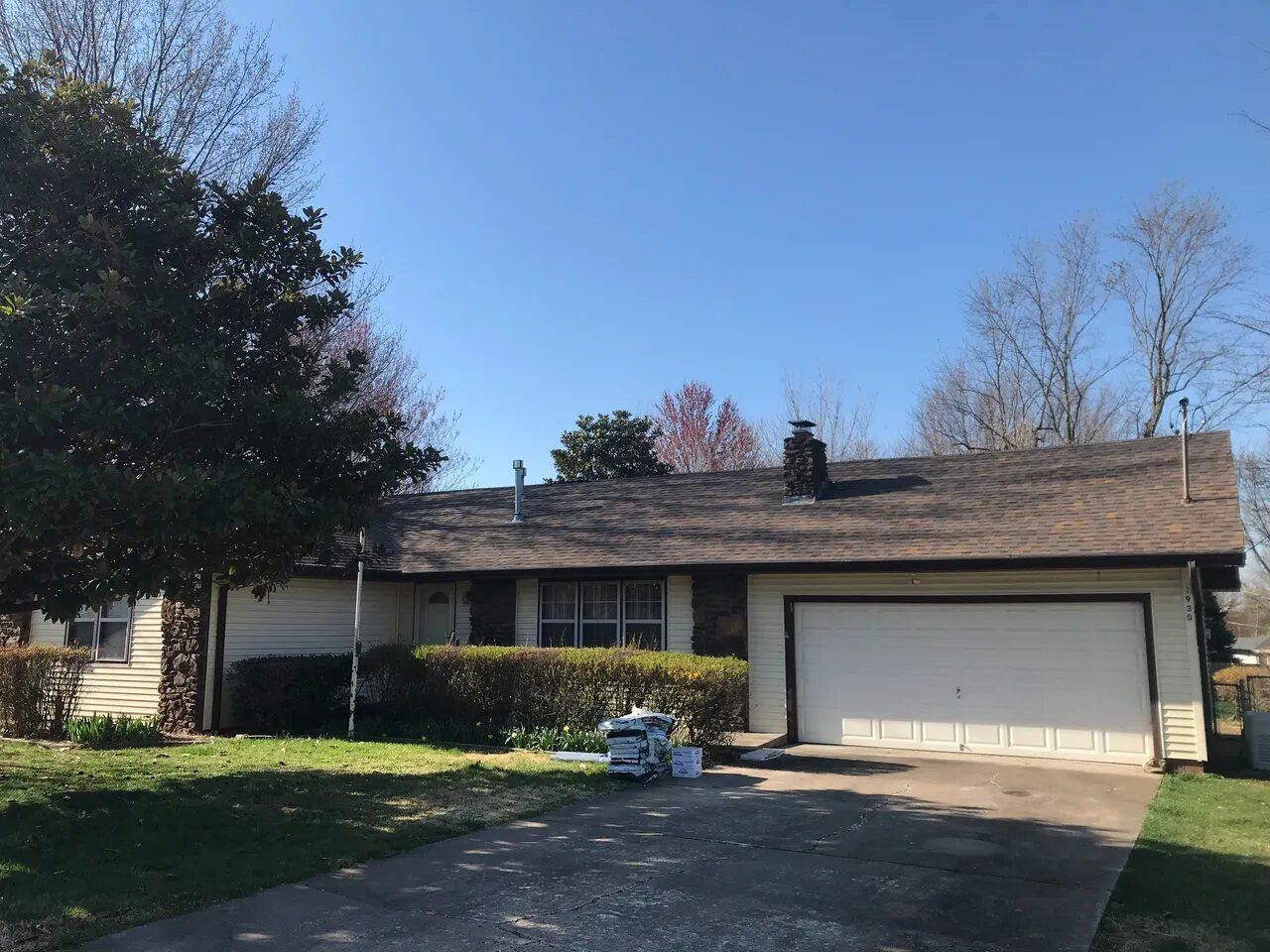 A white house with a brown roof and a garage.