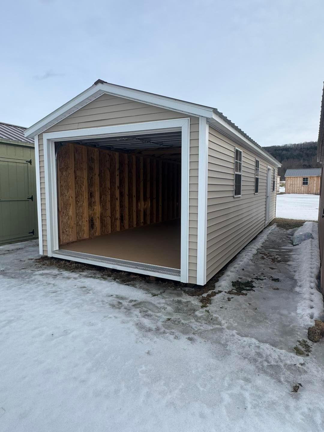 A garage is being built in the snow with the door open.