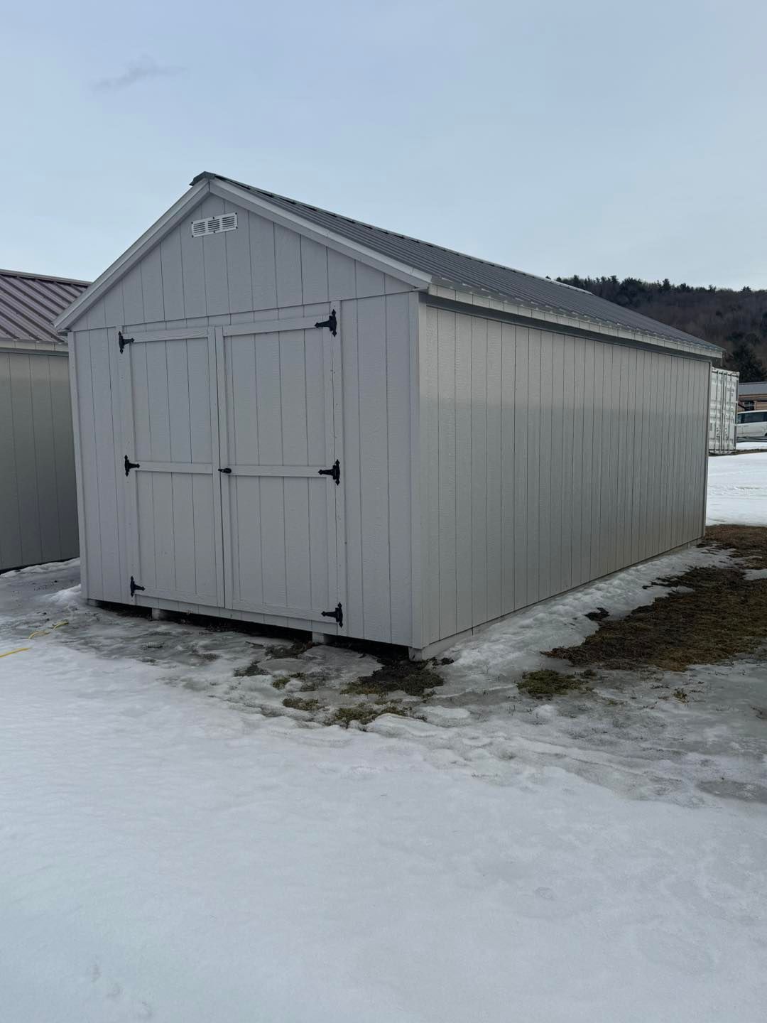 A white shed is sitting in the middle of a snowy field.