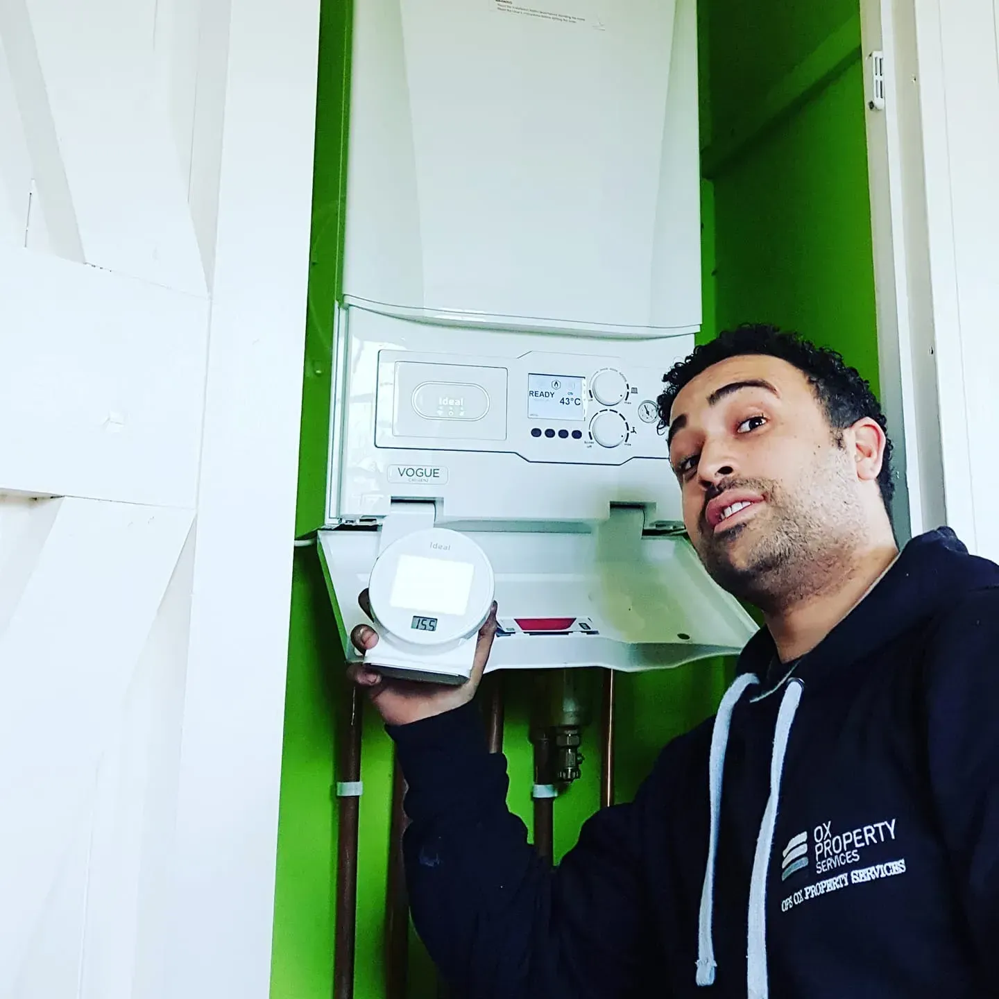 A man is holding a device in front of a boiler.