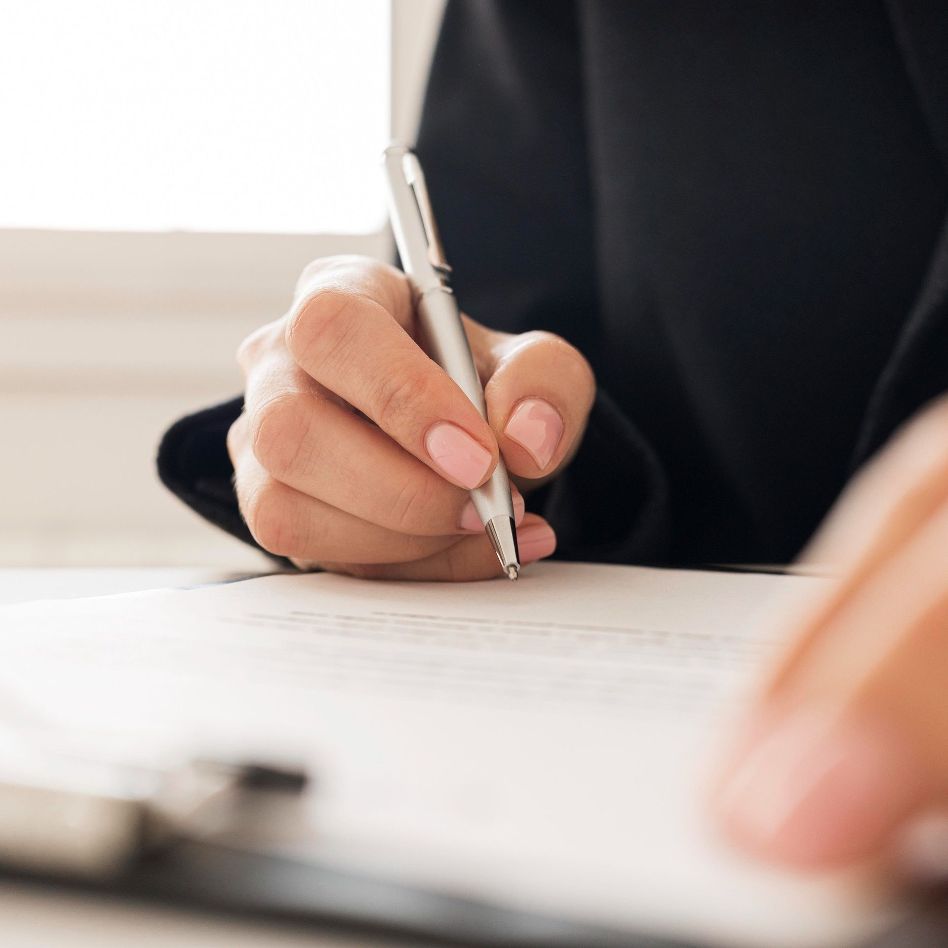 A woman is writing on a piece of paper with a pen