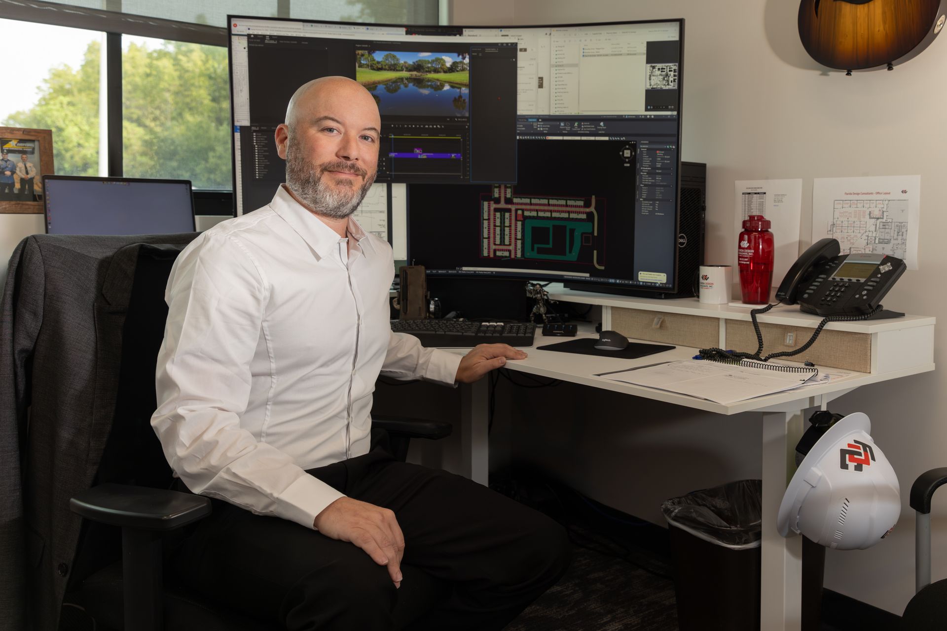 A Florida Design Consultants employee is sitting at a desk in front of a computer at work.