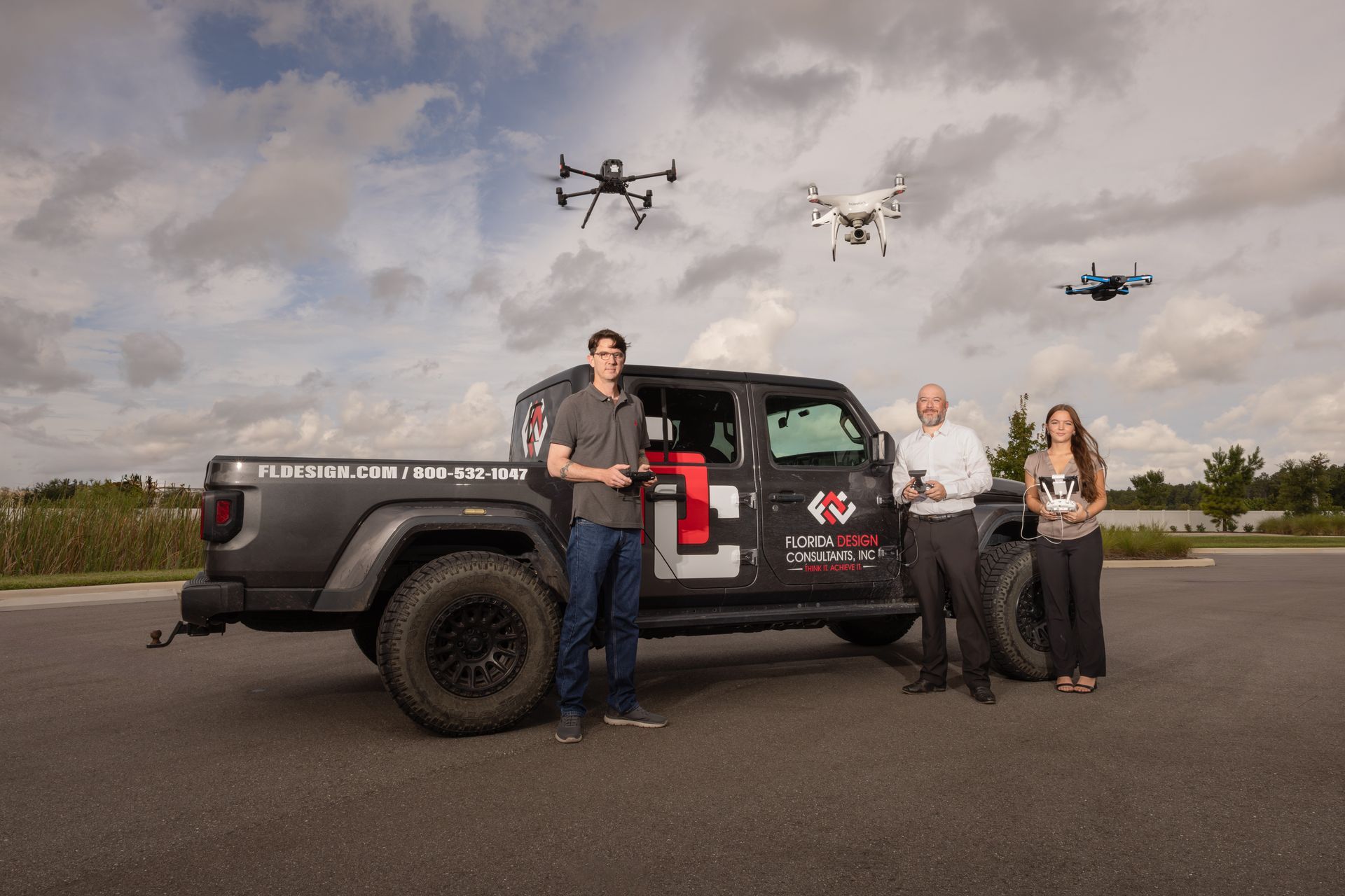 A group of people standing next to a truck with drones flying in the background.