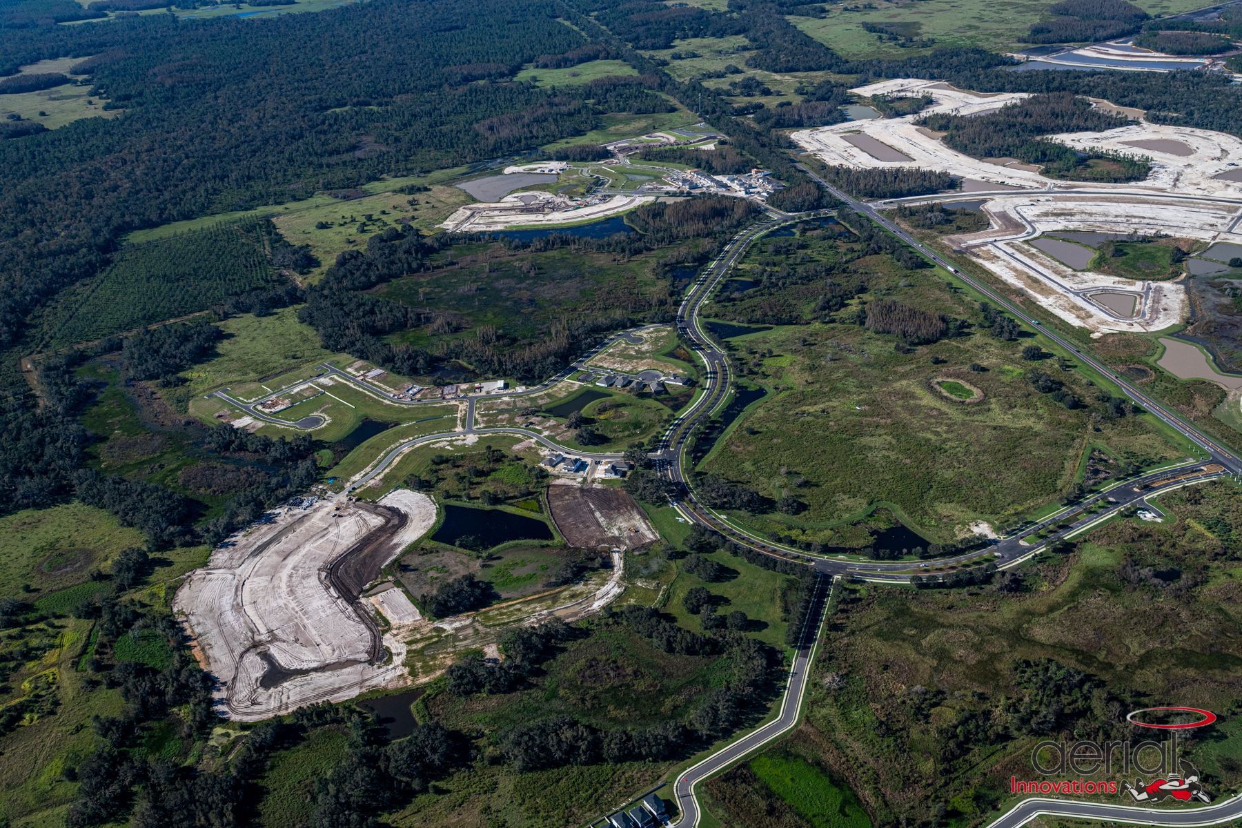 An aerial view of a residential area surrounded by trees and a highway.