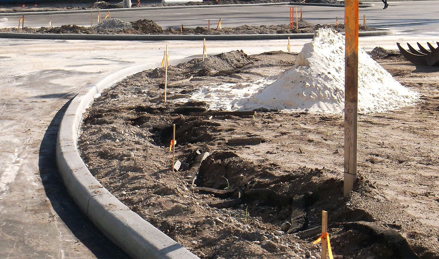 A construction site with a pile of dirt in the middle with stakes around it.