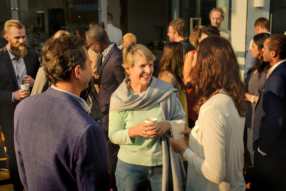 A group of people are standing around talking to each other at a community event sponsored by Florida Design Consultants