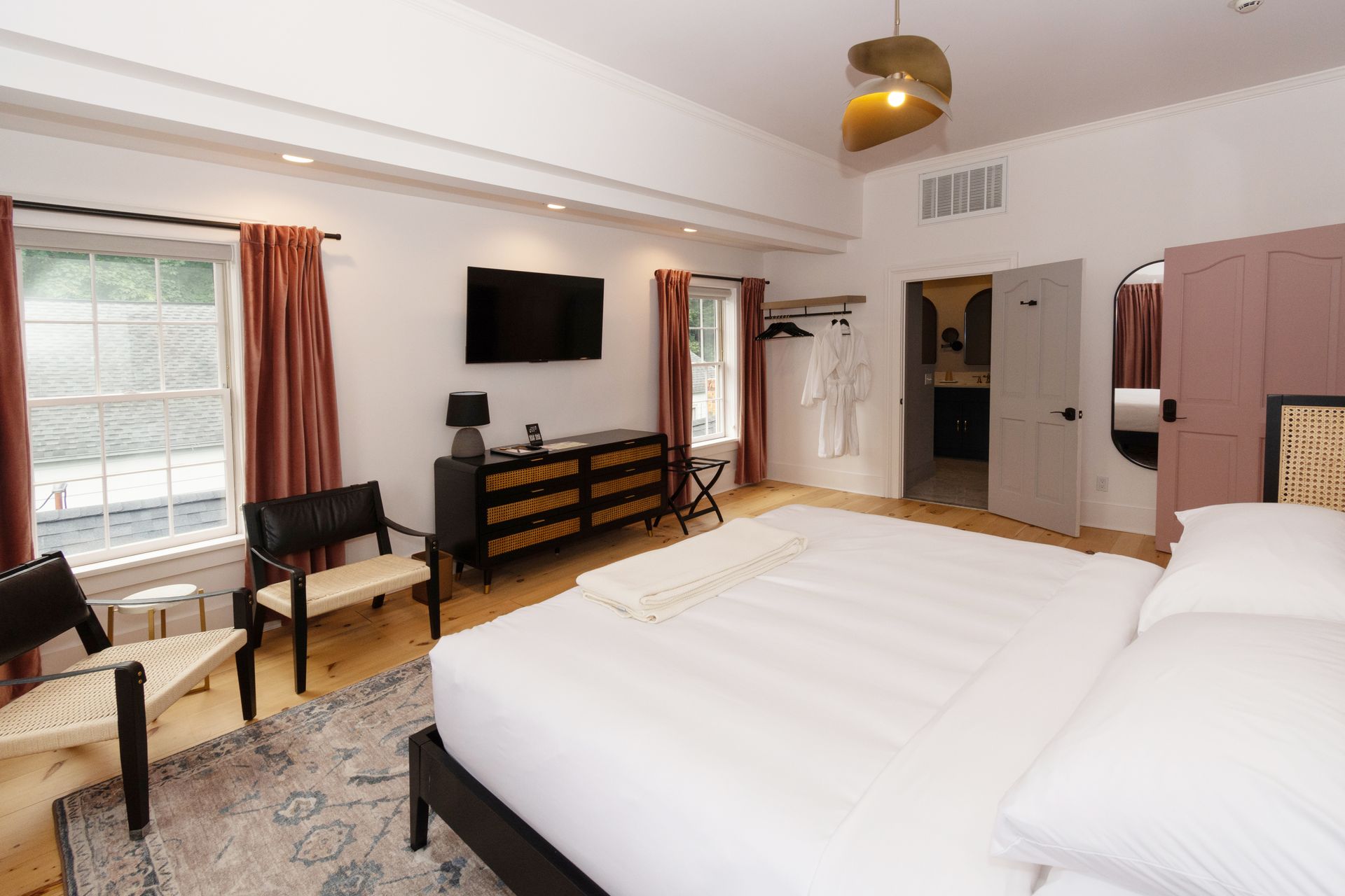 Picture of the room called Brayfeaturing a king bed with four windows flanked with long pink drapes.