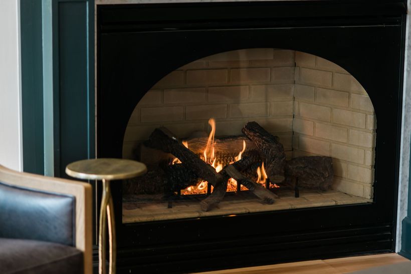 a burning fireplace with nearby seat and drink stand