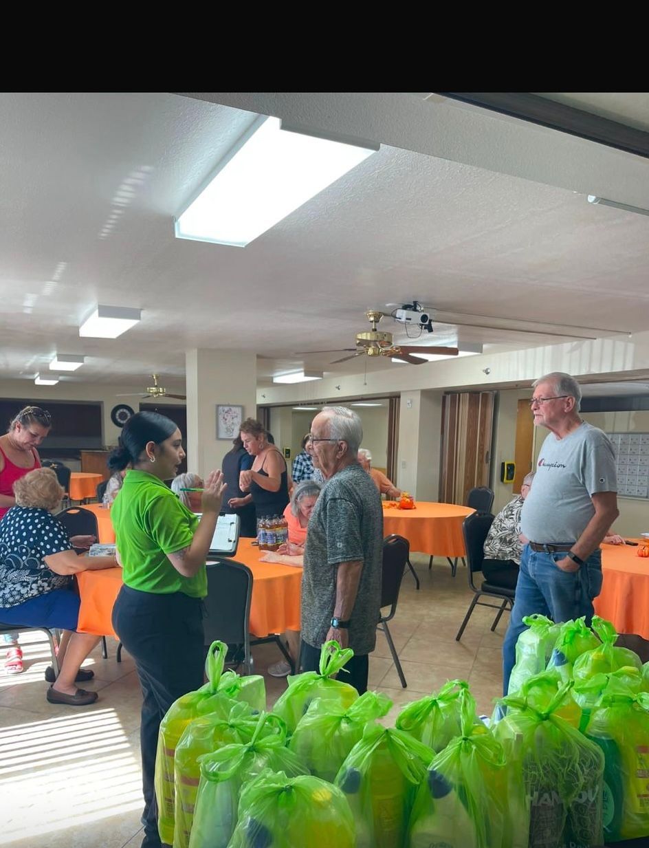 A group of people are standing in a room with bags of food.