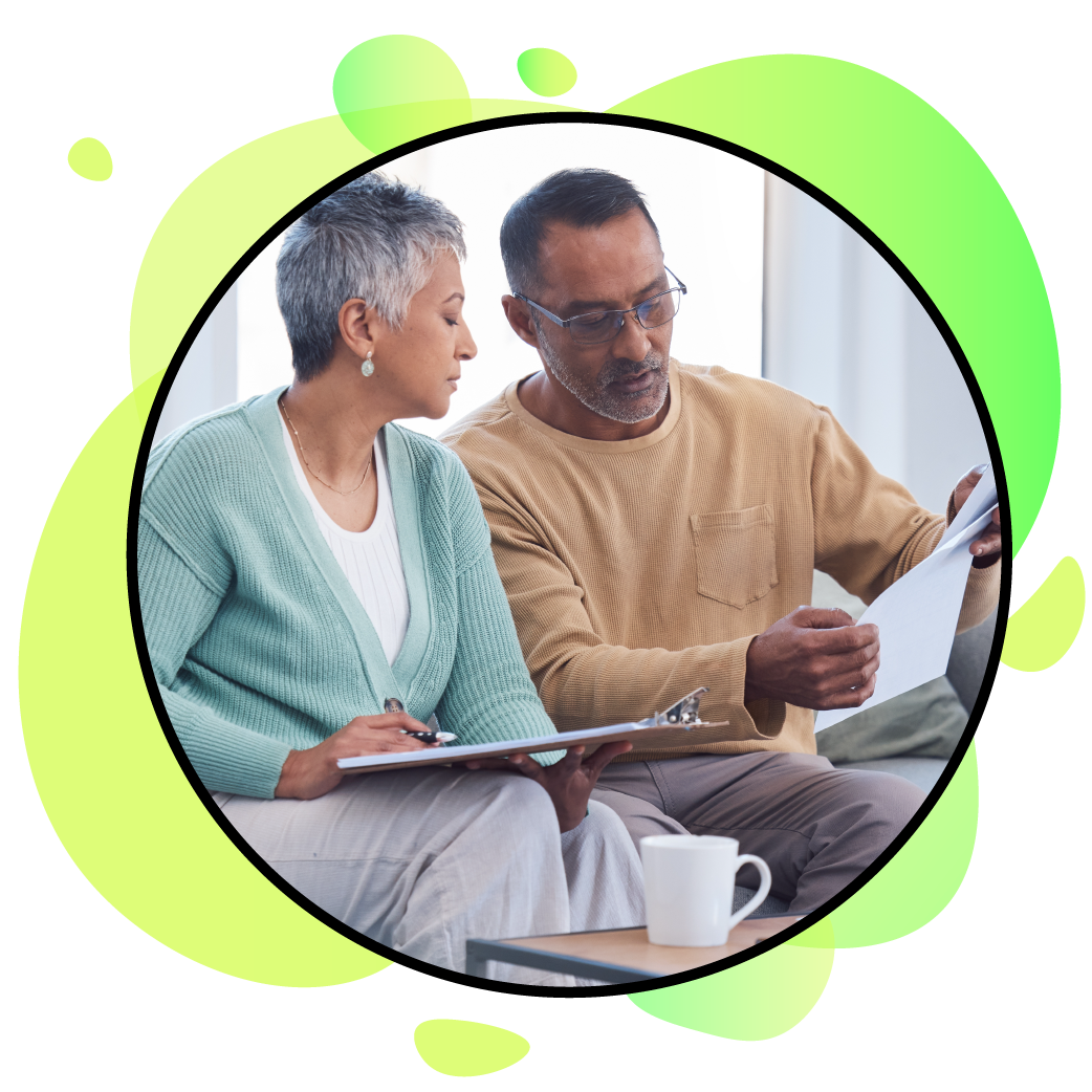 A man and a woman are sitting on a couch looking at a tablet.