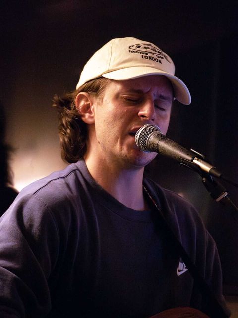 A man sings and plays the guitar in a restaurant.