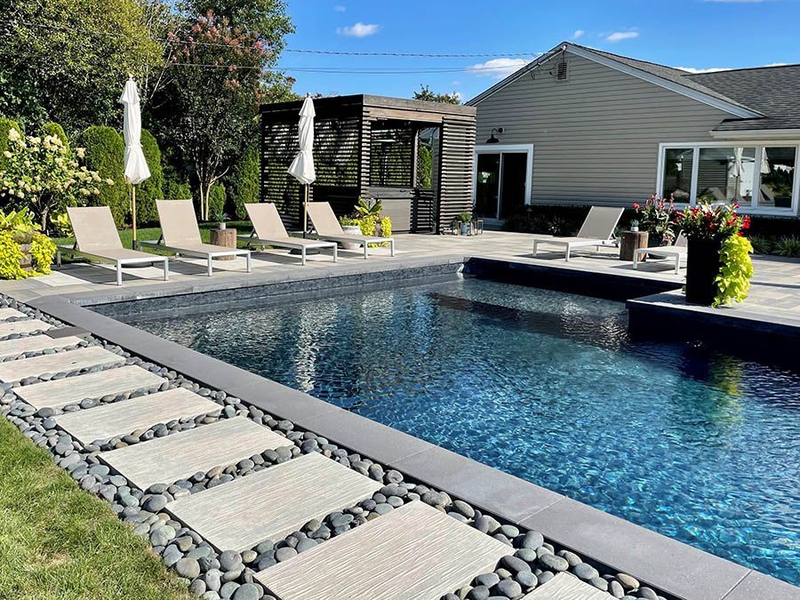 A large swimming pool with chairs and umbrellas in front of a house.