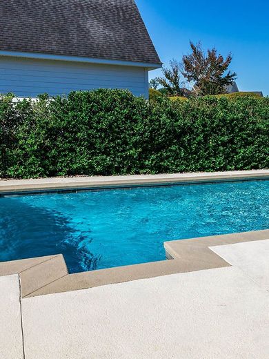 A large swimming pool with a house in the background