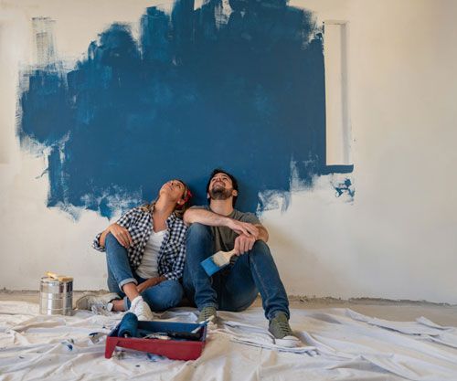 Un hombre y una mujer están sentados en el suelo frente a una pared azul.